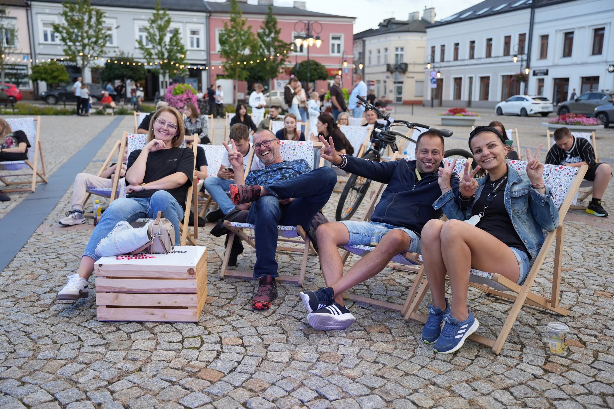 Uczestnicy festiwalu siedzący na rynku podczas koncertu